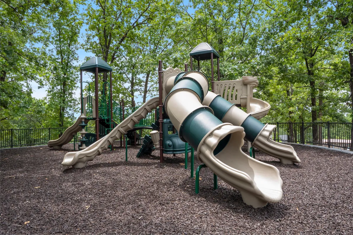 An outdoor playground with slides and play structures surrounded by trees, offering a joyful and safe environment for children to play and families to gather.