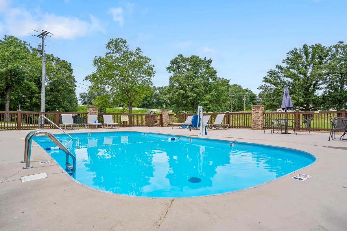 A sparkling swimming pool fringed by lounge chairs and lush greenery, creating a relaxing space for swimming, sunbathing, and socializing under the sun.